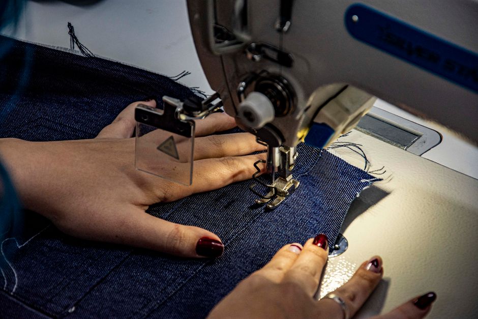 Detailed shot of sewing denim fabric on a sewing machine, highlighting craftsmanship and textile work.